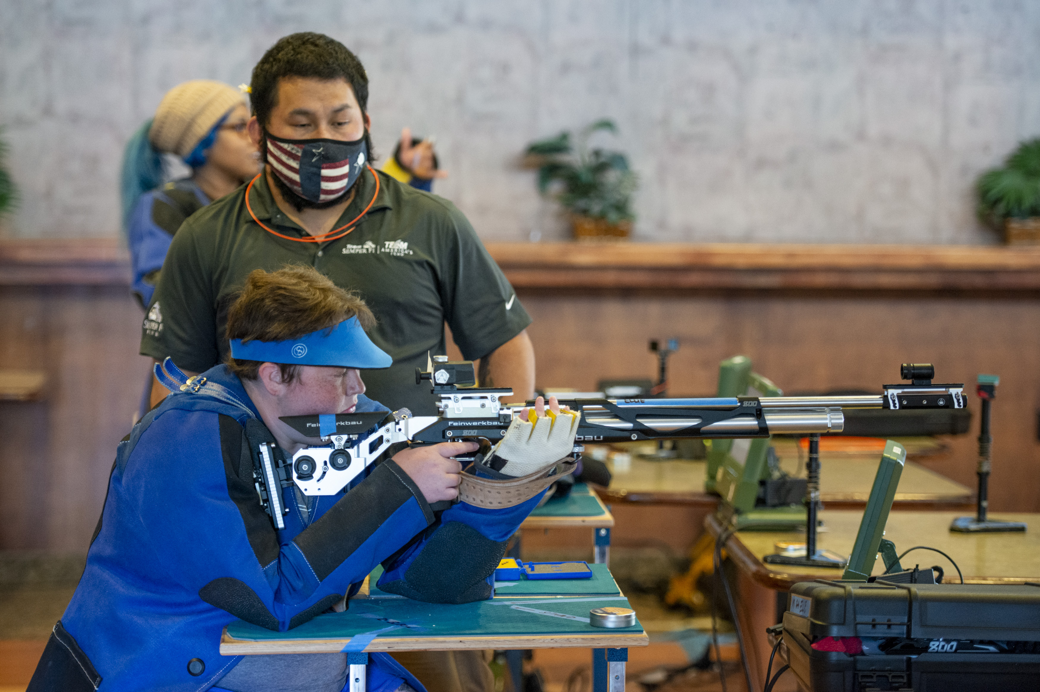 Coach Roel Espino assists Retired AZ3 Elizabeth “Ellie” Smith with air rifle during the Navy Warrior Games Training Camp at Port Hueneme - Naval Base Ventura County, California